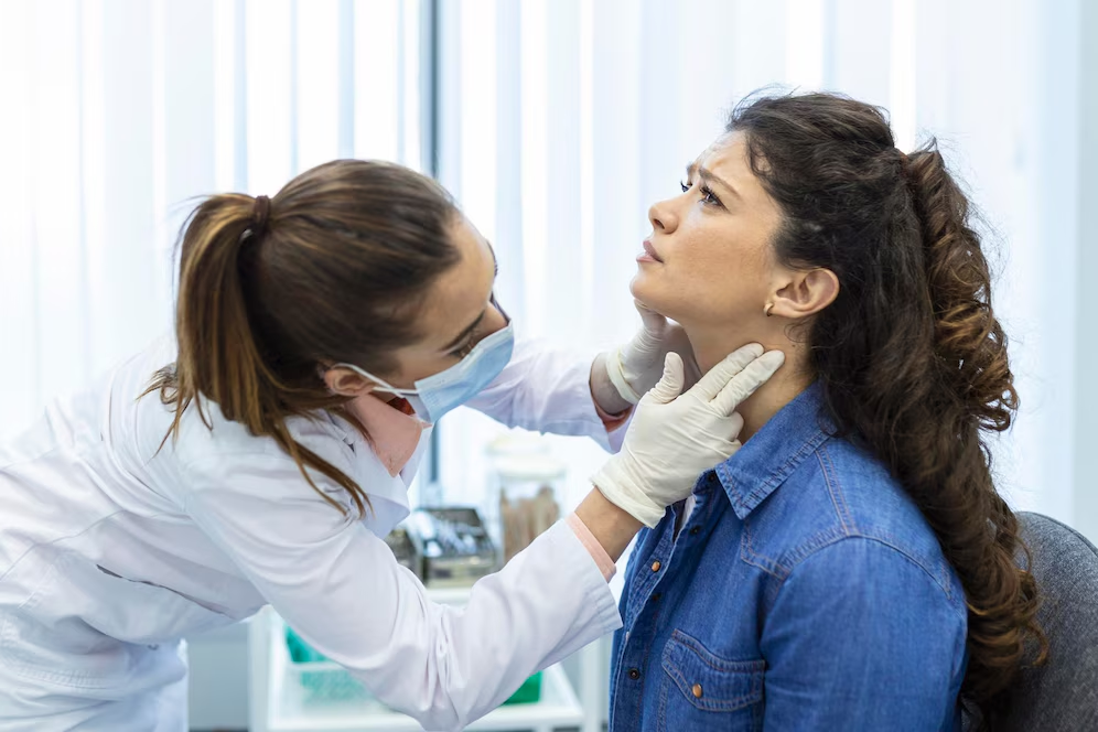 Endocrinologist examining throat of young woman