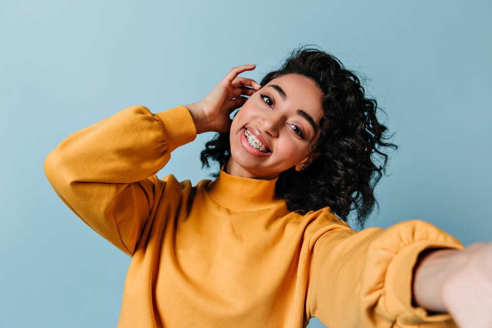 Pleased woman in dental braces taking selfie